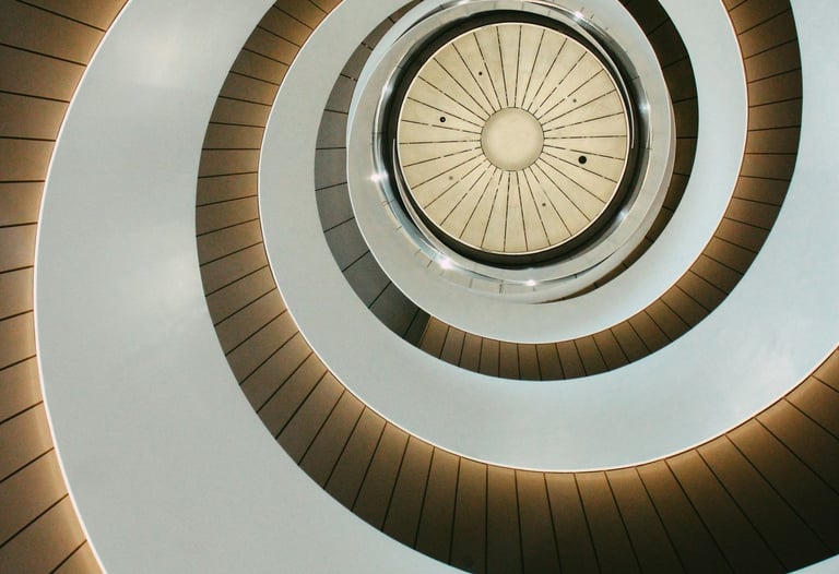 Low angle view of a modern spiral staircase with minimalist white walls and integrated lighting.