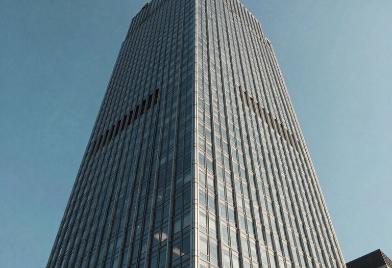 A perspective shot of a modern glass skyscraper in a North American city against a clear blue sky. The steel and glass facade represents scalability and high-tech efficiency.