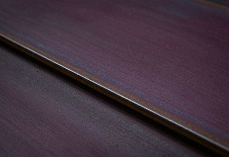 Close-up of high-quality industrial recycled steel plates with a subtle brushed texture, moody low-key lighting in deep aubergine and black, professional and authoritative tone.