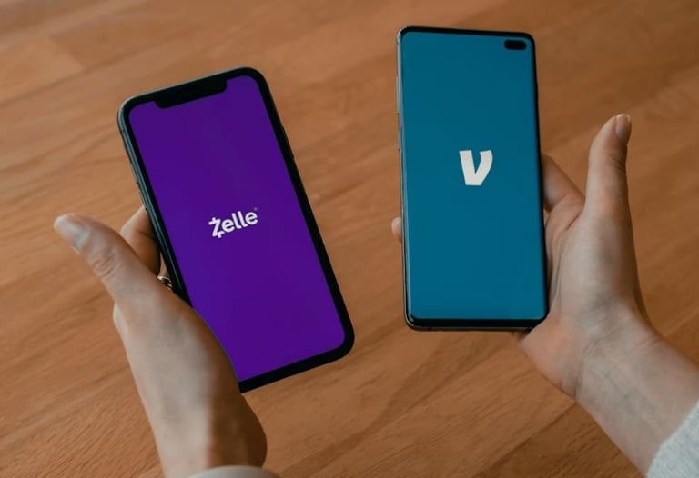 Person holding two smartphones displaying the Zelle and Venmo mobile payment app logos.