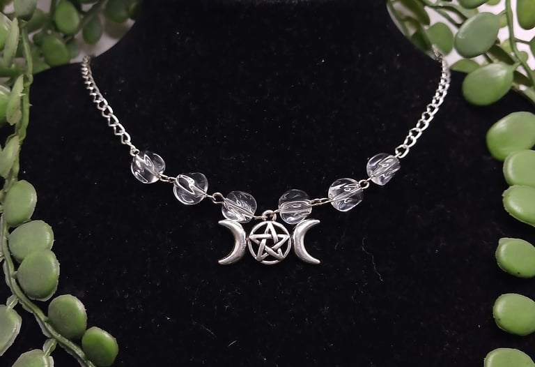 Silver triple moon goddess pentacle necklace with clear crystal beads on a black jewelry display bust.