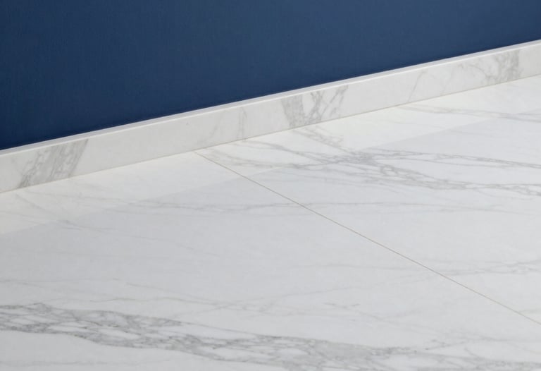 Detailed photography of a premium white marble floor meeting a deep blue wall, representing the high-end material sourcing capabilities of the firm.