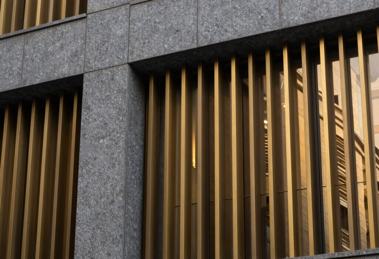 Detail of a modern building facade featuring graphite grey stone and golden metallic slats, reflecting a sophisticated South American design aesthetic.