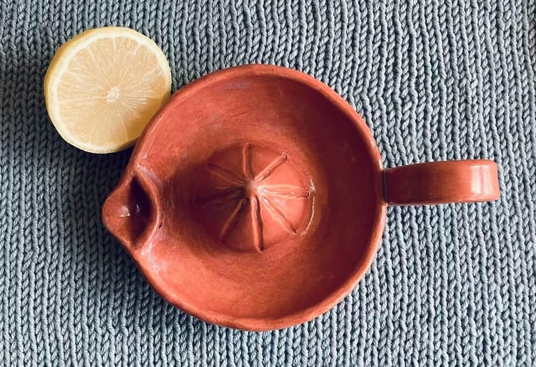 A handmade ceramic lemon juicer on a knitted background