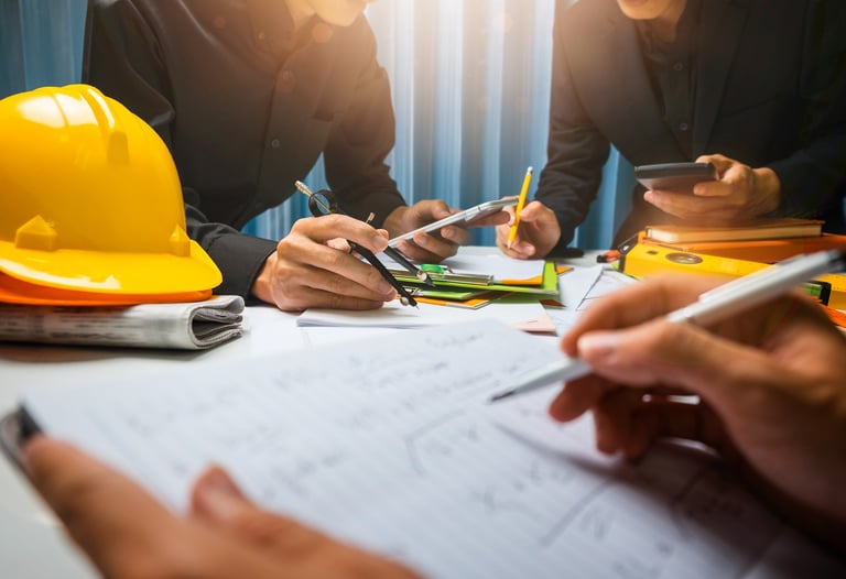 A group of people looking over detailed drawings and making calculations