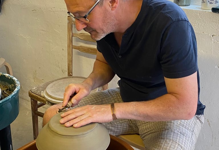 a man is making a clay potted potted with a wheel