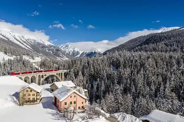 Bernina Express crossing a stone viaduct over a snowy village