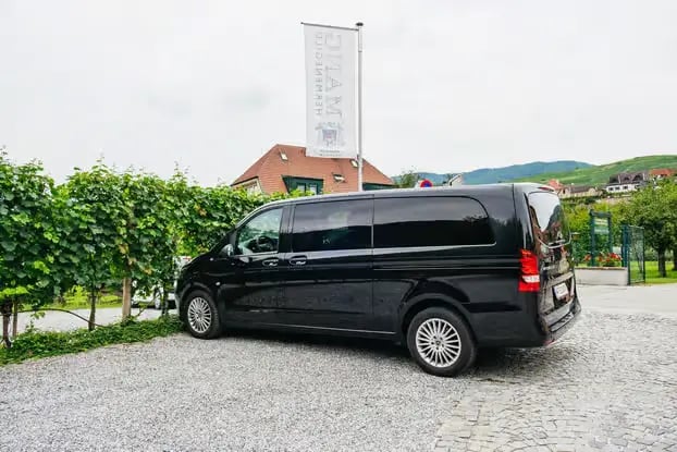 A sleek black Mercedes van parked by a vineyard for a private Wachau Valley tour.