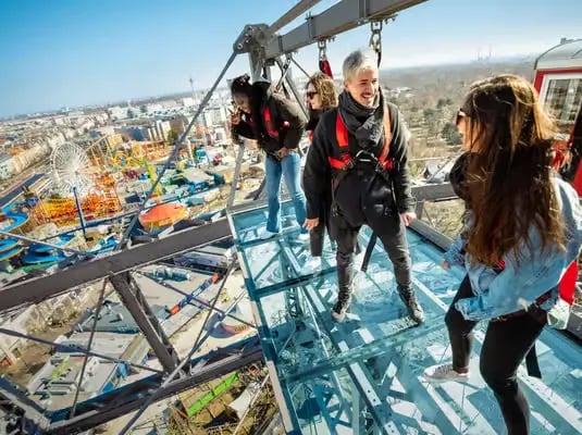 Tourists standing on the glass-bottom Platform 9 of the Vienna Giant Ferris Wheel.