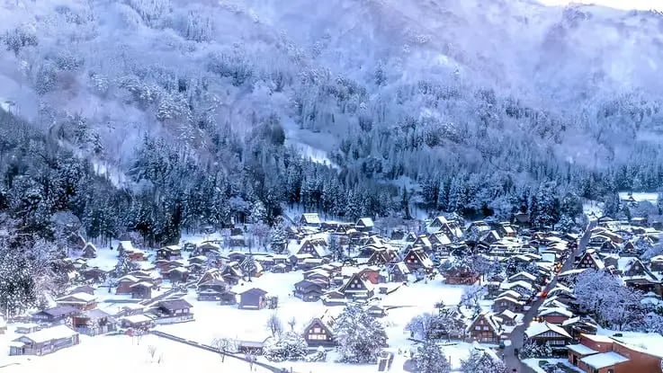 Panoramic view of snow-covered Shirakawa-go village and forest.