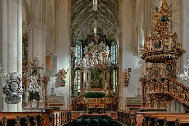 Interior view of a historic cathedral with a golden altar in Graz.