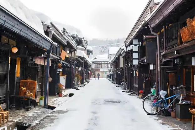 Snowy street lined with traditional Japanese wooden buildings.