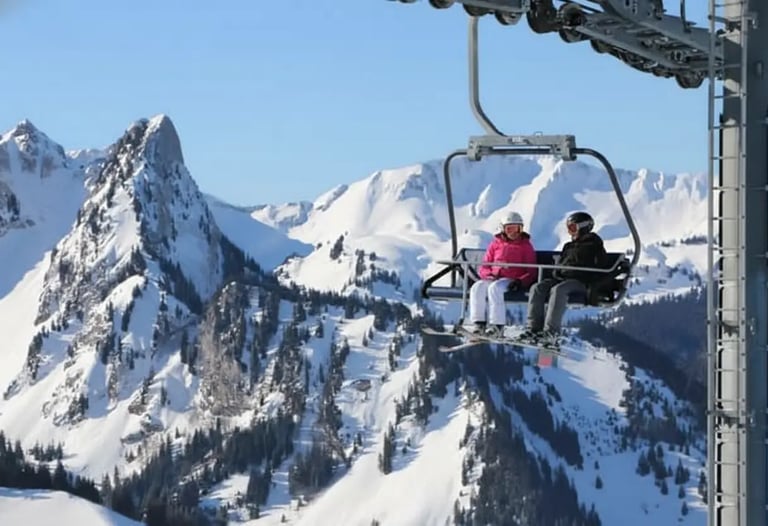 Skiers riding a chairlift over rocky mountain peaks in a Swiss ski resort.