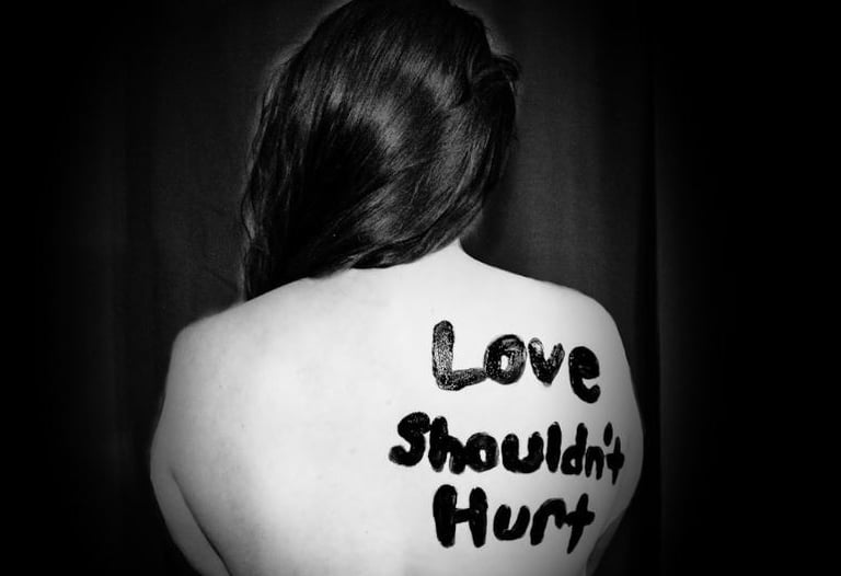 a woman domestic violence survivor with the words love shouldn't hurt on her back