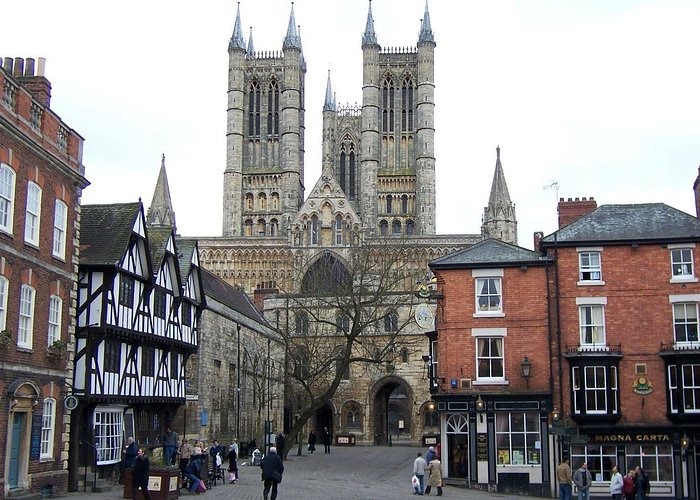 The historic Lincoln Cathedral towers over traditional Tudor architecture in Lincoln's medieval Castle Hill square.