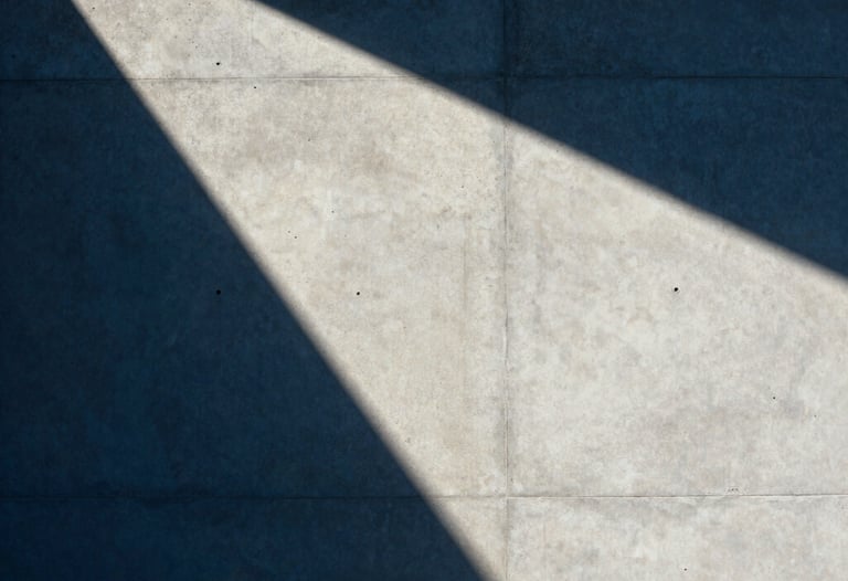 Abstract photography of architectural shadows on a concrete wall. Sharp lines, deep blue and crisp off-white tones, minimalist Latin American / Hispanic style.