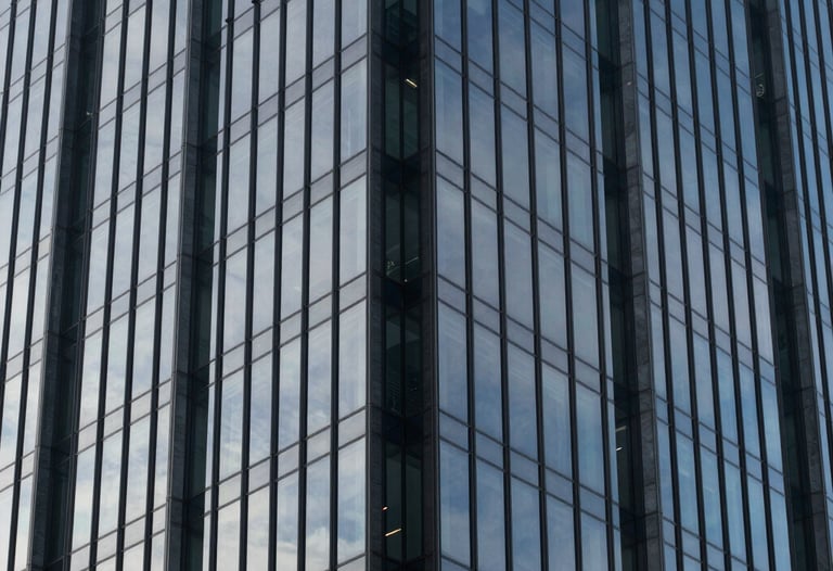 Photography of a modern glass skyscraper reflecting a clear sky. High-contrast composition in Oxford navy and slate gray blue tones. Represents stability and growth.