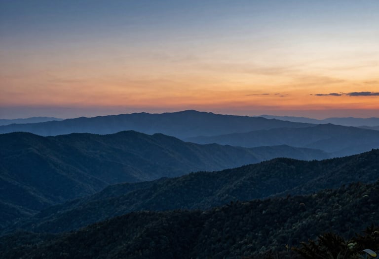 A distant shot of layered mountain ridges under a deep blue and orange sky at sunset, depicting beautiful clean vistas of the Blue Ridge Parkway.