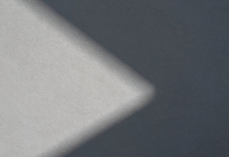 Abstract composition of light and shadow on a textured grey wall in Lisbon. Minimalist, artistic photography highlighting shape and form.