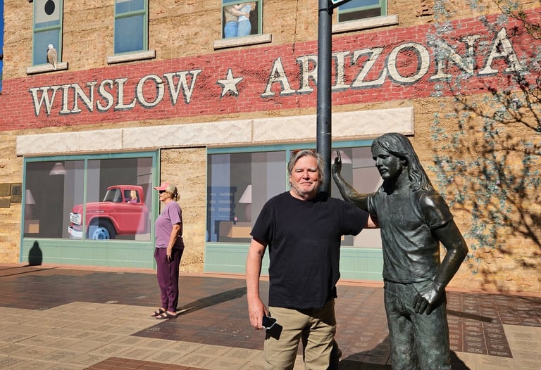 A tourist stands by the Glenn Frey statue at Standin' on the Corner Park in Winslow, Arizona.