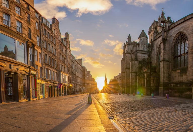 Royal Mile Edinburgh at sunrise with St Giles Cathedral and golden sunlight on empty cobblestones