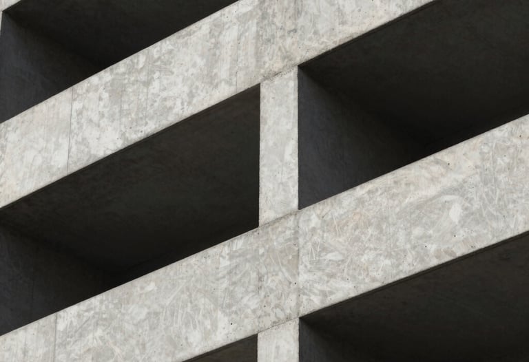 A close-up of high-quality architectural concrete work on a building facade, with sharp shadows creating a play of light. The finish is smooth and premium.