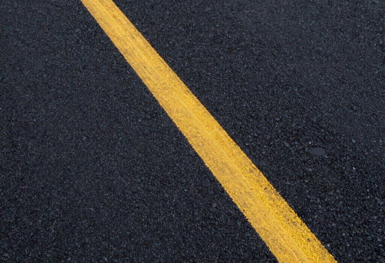 High-resolution photography of a modern asphalt texture with painted yellow lines, symbolizing quality road construction and communication routes.