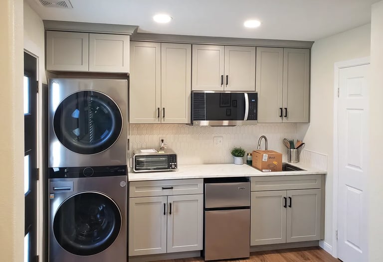 Laundry and kitchenette area with light blue cabinets and stainless steel appliances.
