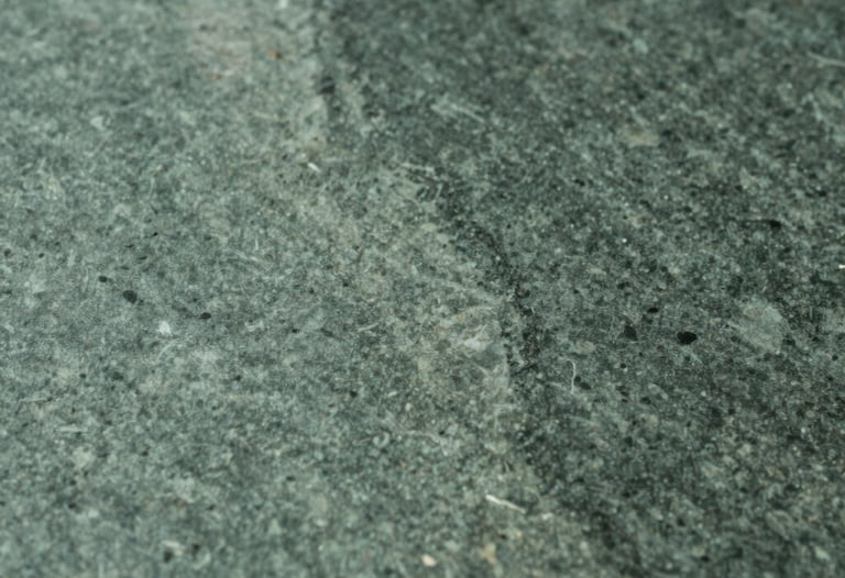Abstract photography of light reflecting off a polished stone surface. Sage green and charcoal green tones. Sophisticated simplicity, South Asian / Global Professional aesthetic.