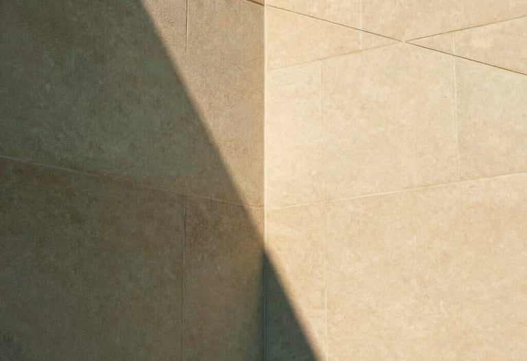 Architectural detail showing the intersection of two smooth sandstone walls. The lighting creates a sharp triangular shadow. Professional, clean, and sophisticated. Warm sand and sage green palette. No living beings.