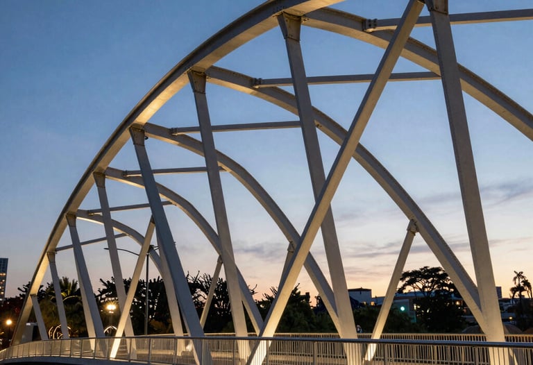 Modern urban park bridge with elegant steel arches at twilight in a North American city. The lighting highlights the geometric strength and aesthetic quality of the civil engineering work.