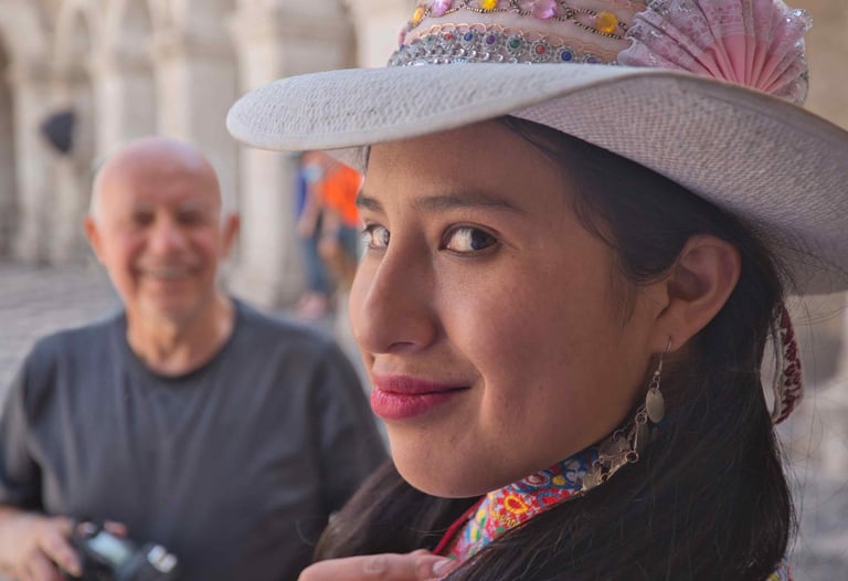 This image shows a woman wearing an embellished hat with colorful beadwork and a pink fan, likely of Peruvian origin.