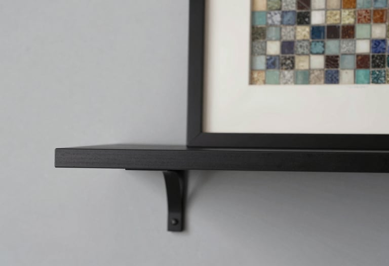 Detail shot of a minimalist black steel shelf against a light grey wall, with a single piece of framed mosaic art, soft shadows, professional photography.