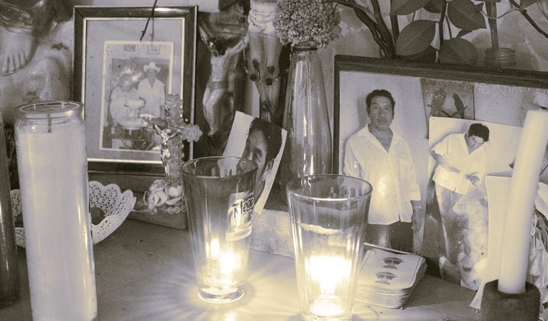 Altar mexicano del Día de los Muertos con fotos familiares antiguas, velas altas de oración