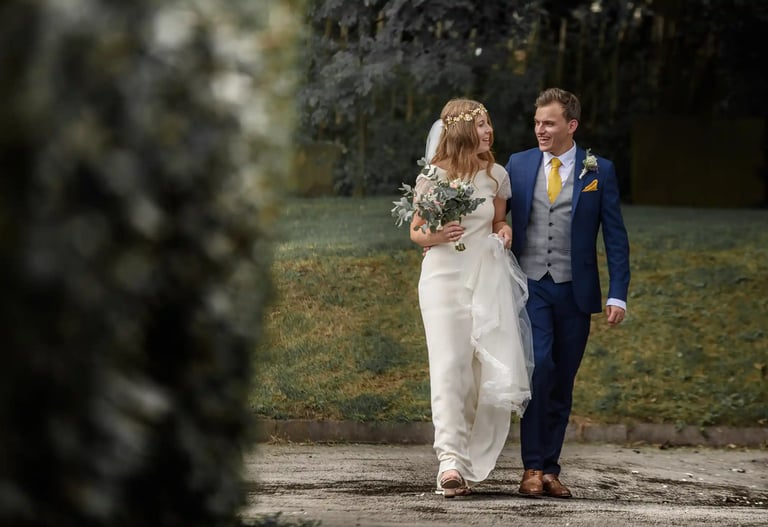 A happy bride and groom walking together outdoors after their wedding ceremony.