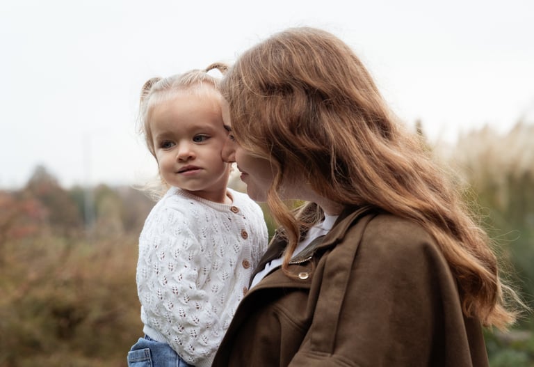 Mother holding her daughter in her arms and smiling at her
