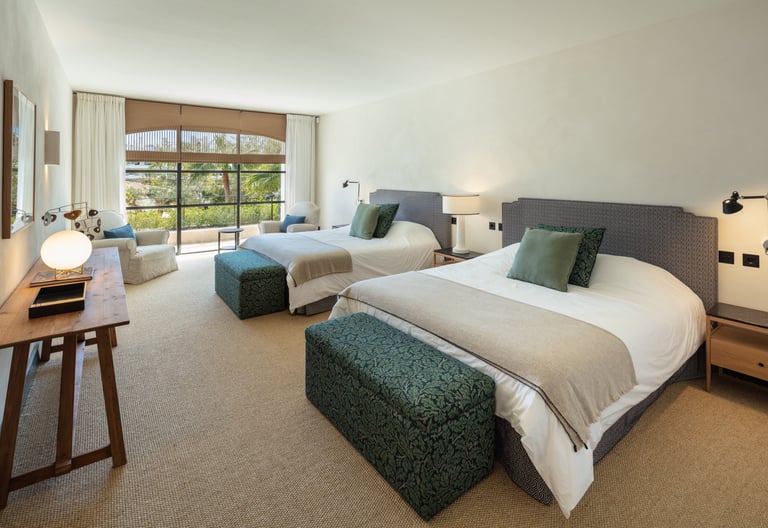 Spacious guest bedroom at Villa La Gratitud with two large beds, garden views, and cozy seating area