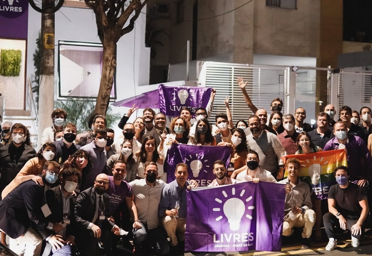 foto de associados do Livres segurando bandeiras do livres na frente da casa livres