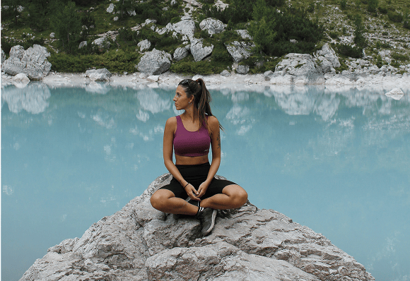 Magui sentada en una piedra sobre un lago