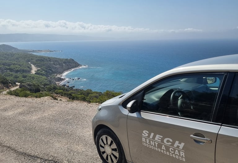A Siech rent a car parked on a scenic coastal overlook with views of the blue Mediterranean Sea and shoreline.
