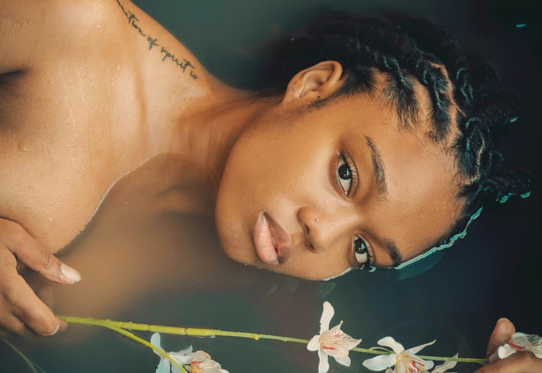 a woman with even-tone skin sitting in a bath of fresh aromatic herbs and spices