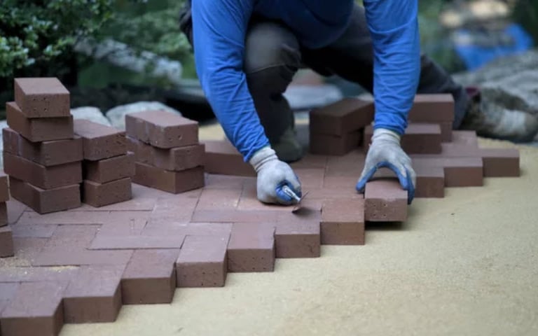 a person laying red brick in a herringbone pattern
