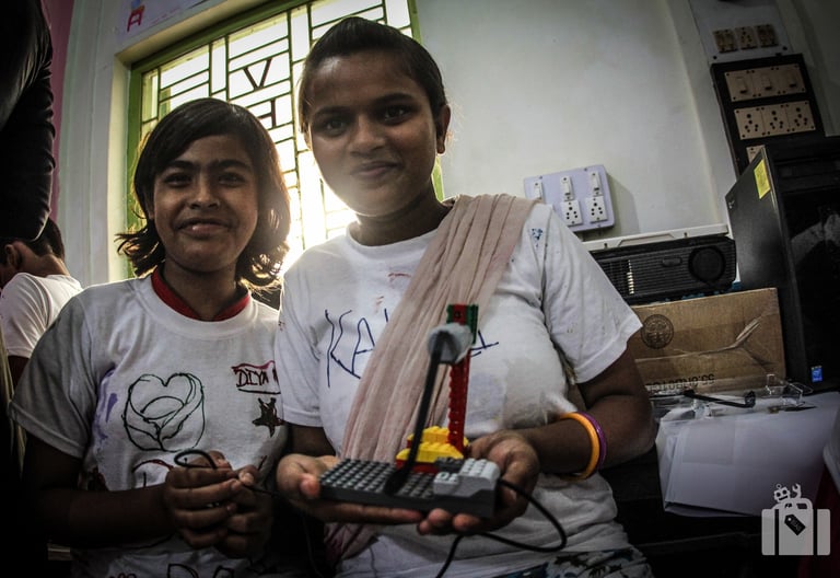 Two students in India proudly display a LEGO WeDo 1.0 robot they programmed, showcasing STEM skills.