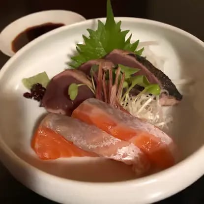 Fresh sashimi with salmon and tuna in white bowl with garnish
