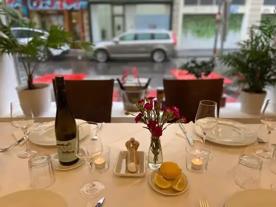 A set table with wine bottle, wine glasses, candles and fresh flowers prepared for guests at a Vienna cooking class