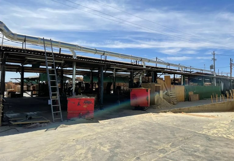 Patio industrial maderero con ductos plateados de un sistema de transporte neumático