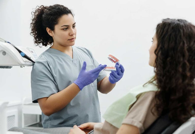 Dentista explicando a paciente sobre las protesis dentales, sosteniendo una protesis dental
