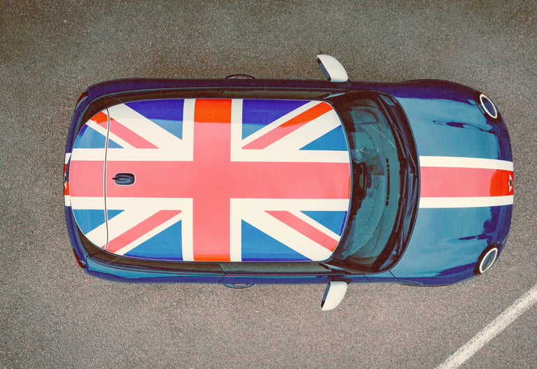 Aerial view of a blue Mini Cooper featuring a Union Jack flag roof decal parked on asphalt.
