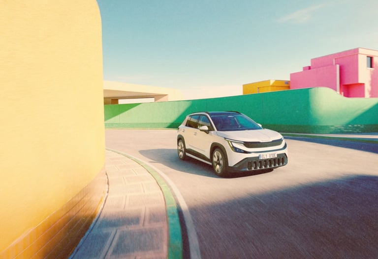 White Skoda Epiq electric SUV driving on a road surrounded by colorful pastel buildings.