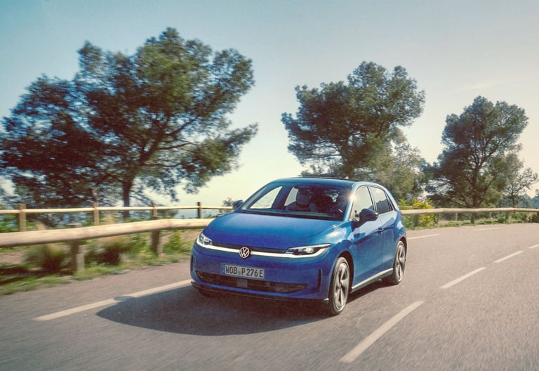 Blue Volkswagen ID. Polo electric car driving on a scenic winding road with trees.